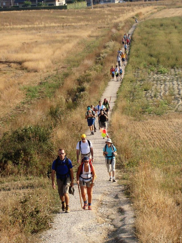 Un gruppo WeRoad percorre in fila indiana uno stretto sentiero sterrato che si snoda attraverso un paesaggio arido ed erboso.