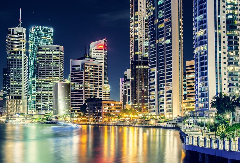 Uno skyline urbano con grattacieli illuminati che si riflettono su un fiume di notte.