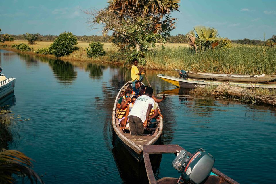 Un viaggio di gruppo WeRoad in canoa di legno lungo un fiume calmo e stretto, circondati da una vegetazione lussureggiante.