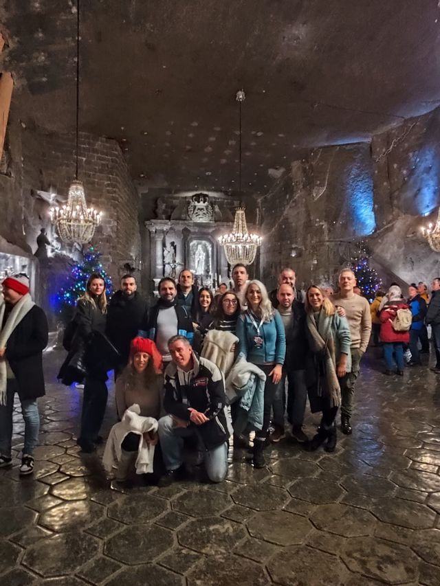 Un viaje en grupo de WeRoad posa para una foto dentro de una caverna de roca decorada con candelabros de cristal y una capilla tallada.