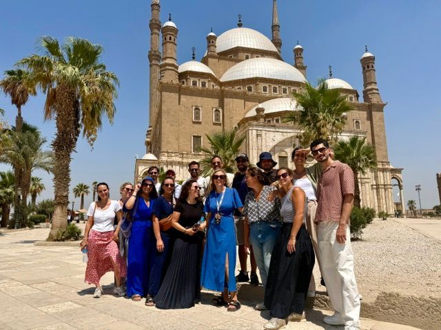 Un groupe WeRoad pose pour une photo devant une grande mosquée historique avec plusieurs dômes et minarets.
