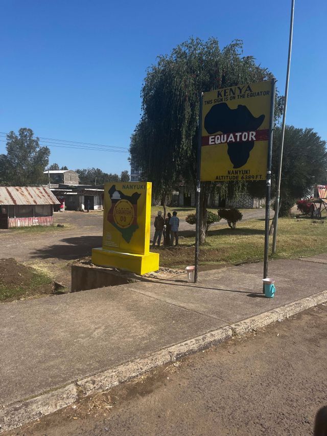 Two large yellow signs indicating the Equator line in Nanyuki, Kenya, standing by a road under a clear sky.