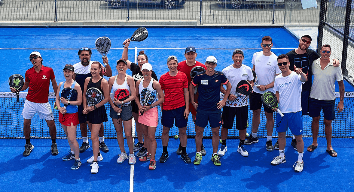 Una foto dall'alto di un gruppo WeRoad in posa su un campo da padel blu con le racchette in mano.