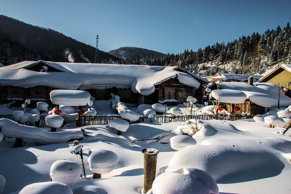 Cabañas de madera en un pueblo de montaña cubiertas por una gruesa capa de nieve en un día brillante y soleado.