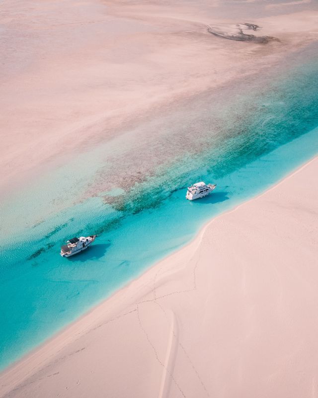 Boats anchored by a white sandbar in the Bahamas