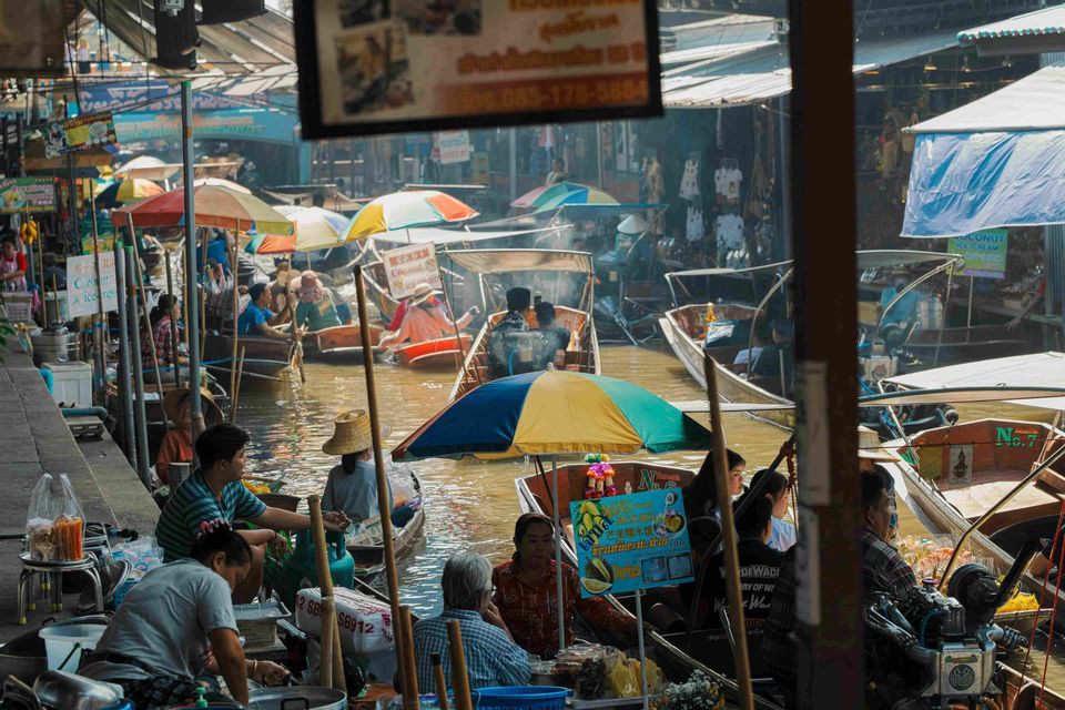 Un vivace mercato galleggiante con molti venditori e turisti su piccole imbarcazioni in un canale affollato.