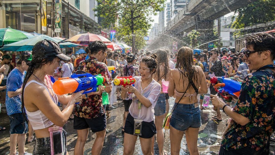 Un gruppo WeRoad in battaglia d'acqua con pistole colorate in una via affollata durante un festival.