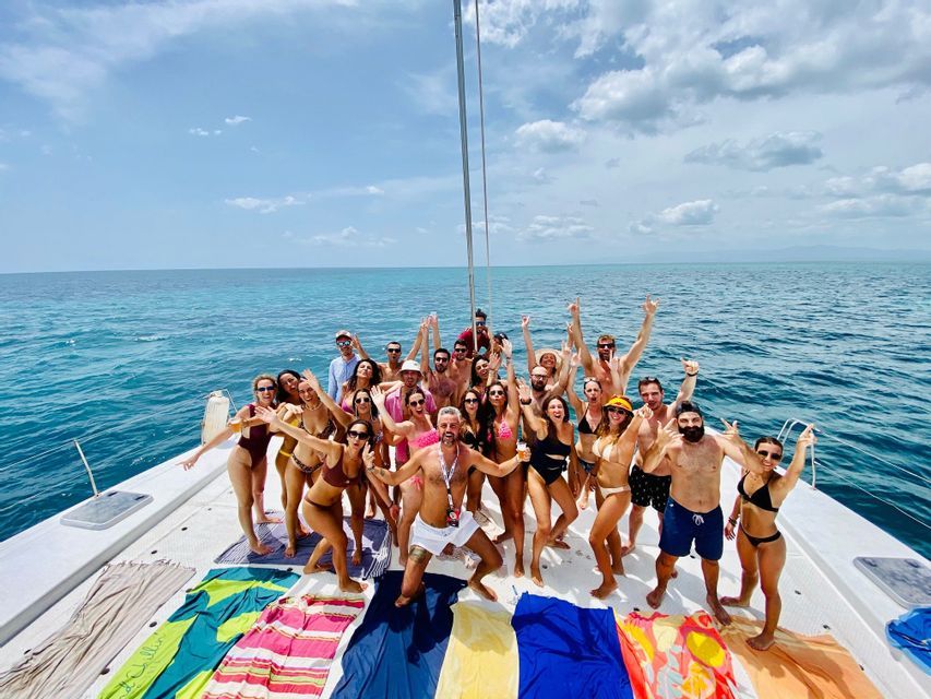 A large WeRoad group trip in swimwear posing for a photo on the deck of a catamaran on the open sea.