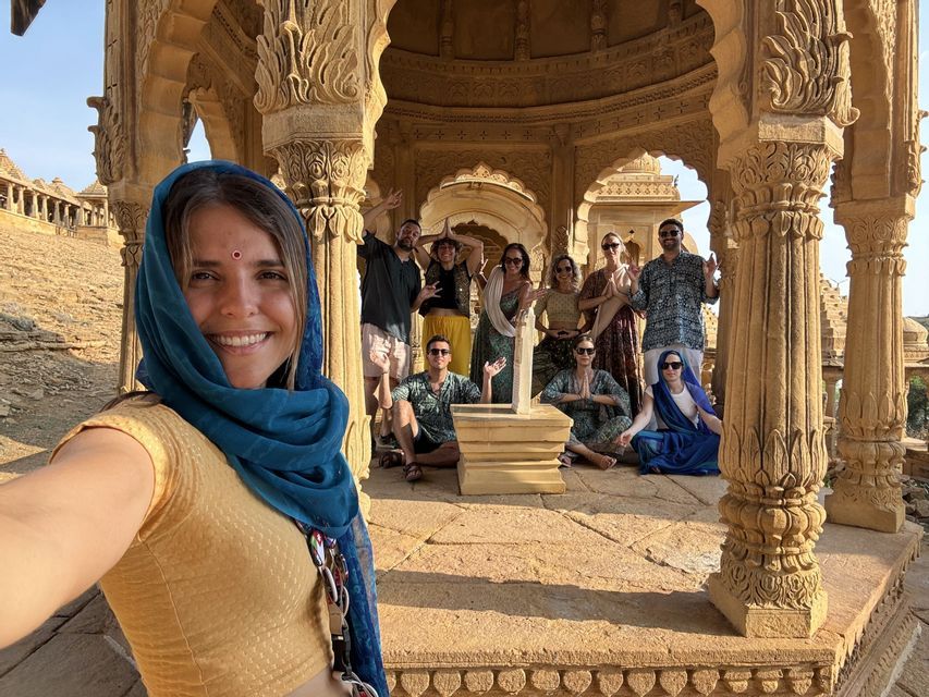 Una mujer con un pañuelo azul se toma una selfie con su viaje en grupo de WeRoad dentro de un pabellón de arenisca ornamentado.