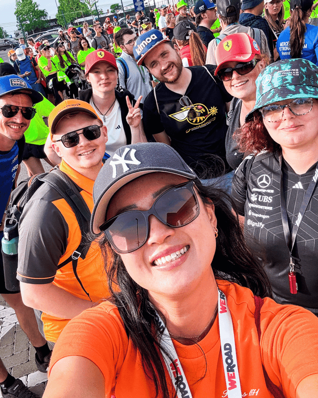 A WeRoad group trip smiles for a selfie photo in a large crowd at an outdoor event.