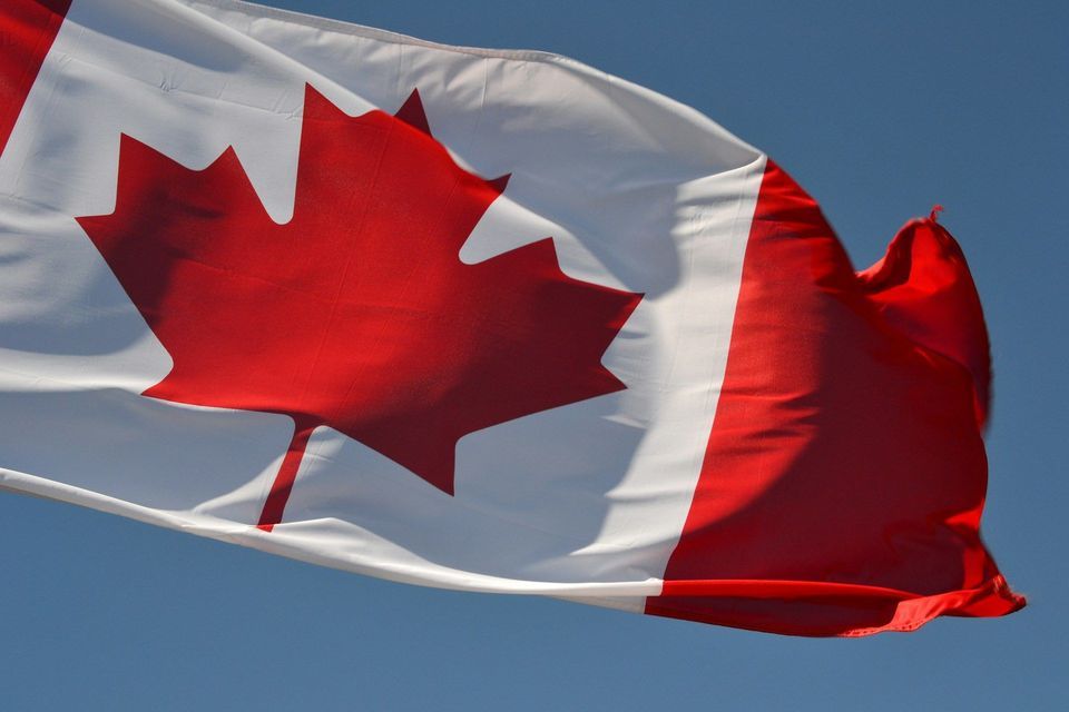 La bandiera canadese, con una prominente foglia d'acero rossa, sventola contro un cielo azzurro limpido.