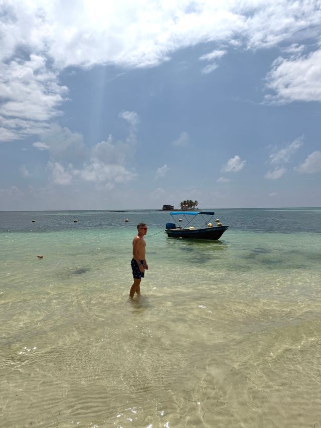 Island hopping in the archipelago Traveler standing in shallow turquoise water next to a small boat during an island hopping tour