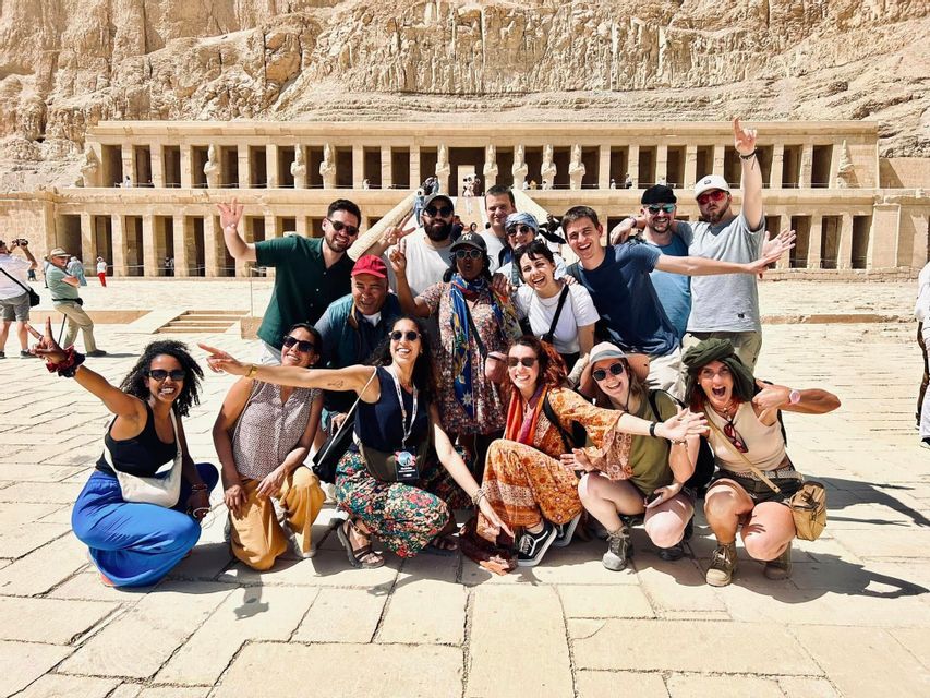 Un gruppo di viaggio WeRoad in posa e sorridente davanti a un antico tempio in pietra con colonne.