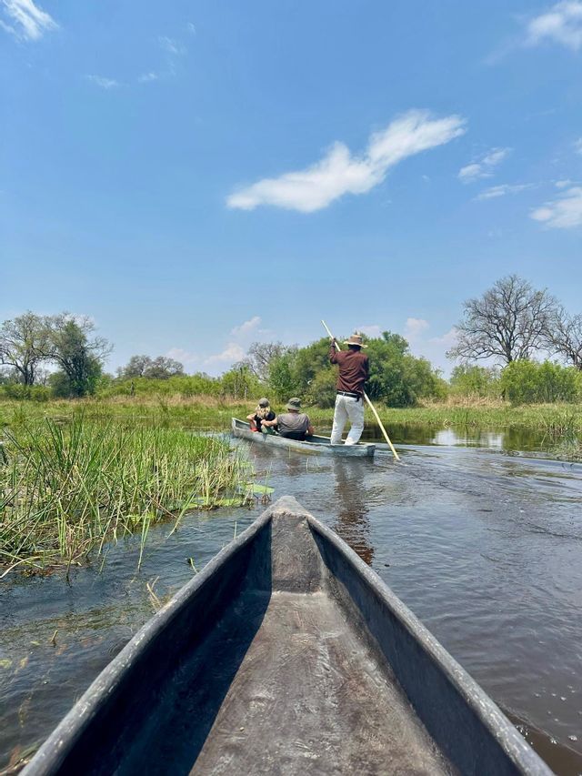 Un viaggio di gruppo WeRoad a bordo di tradizionali canoe scavate nel legno attraverso acque paludose sotto un cielo blu.