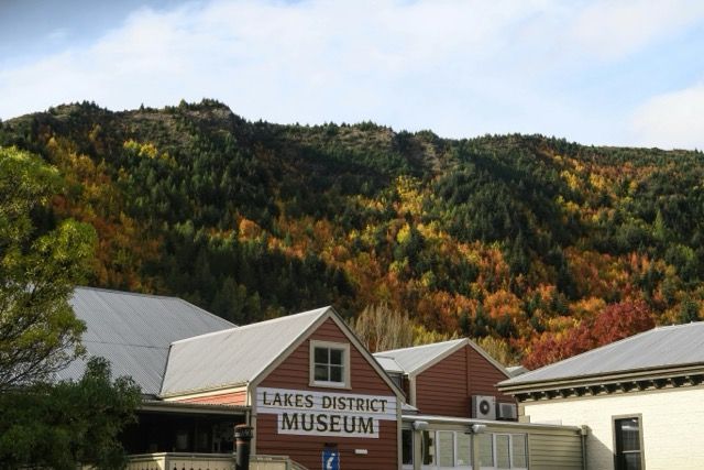 Edificio del museo del distretto dei laghi con un tetto in metallo contro una montagna boscosa con alberi autunnali colorati