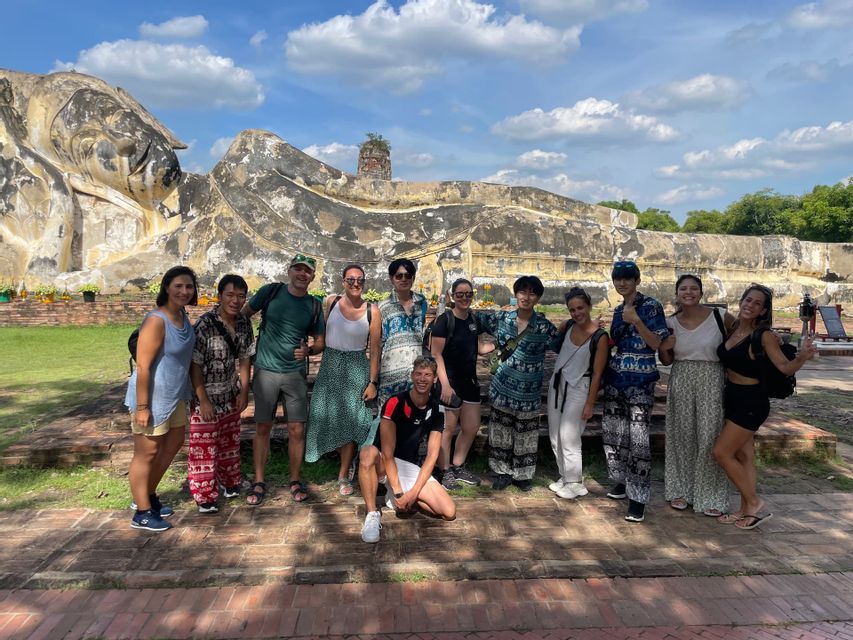 Un voyage de groupe WeRoad posant pour une photo devant une grande et ancienne statue de Bouddha couché.