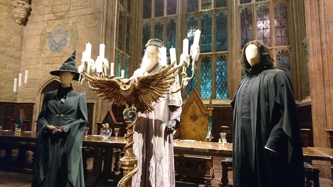 Una mostra di costumi per i personaggi Dumbledore, McGonagall e Snape su manichini in un set cinematografico di una grande sala.