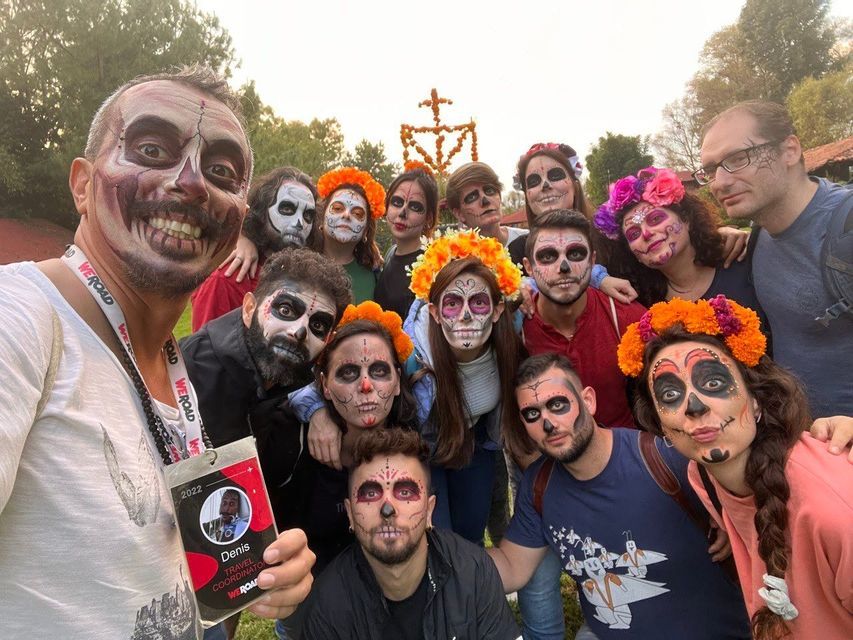 Un grupo de WeRoad posa para una selfie con sus caras pintadas como calaveras, algunos llevando coronas de flores.