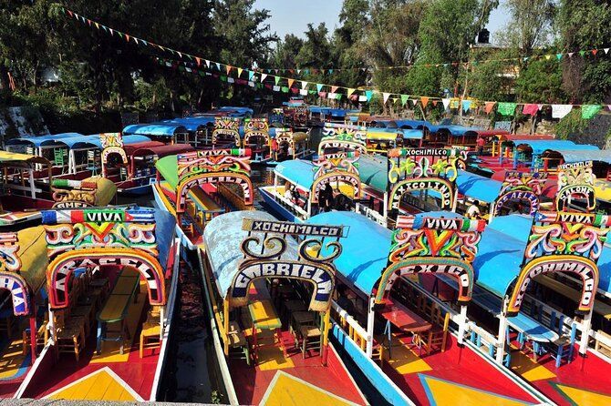 Decenas de barcos coloridos y decorados con entradas arqueadas se agolpan en un canal bajo guirnaldas de banderas.