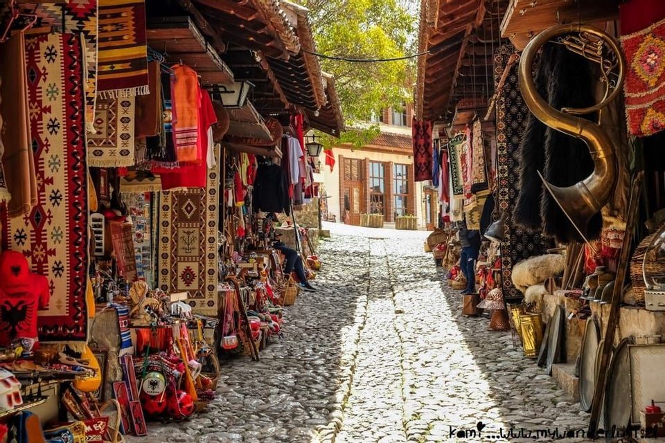 Una callejuela empedrada con puestos al aire libre que venden alfombras coloridas y artesanías locales.