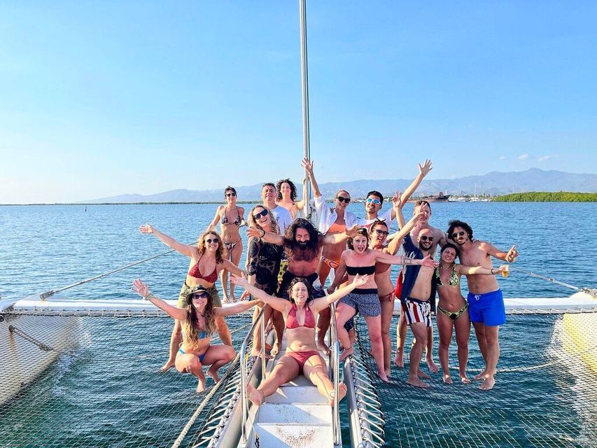 Un gruppo WeRoad in posa sulla rete di un catamarano in mare in una giornata di sole.