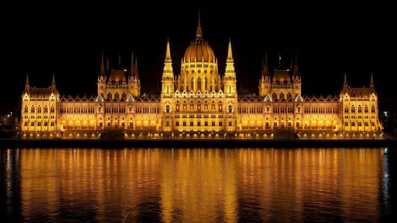The Hungarian Parliament building illuminated and reflected in the Danube at night.