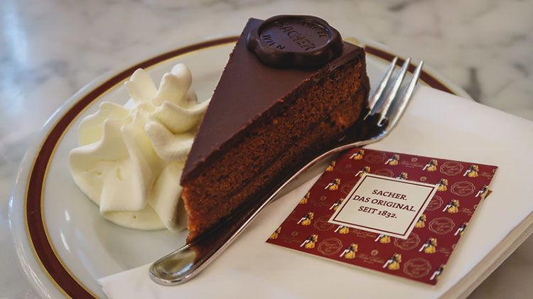 A slice of original Sachertorte with whipped cream on a plate in Vienna.
