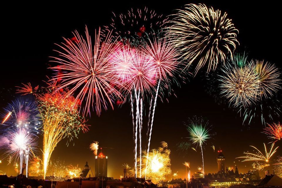 Fuochi d'artificio multicolori che esplodono nel cielo notturno sopra lo skyline illuminato di una città.