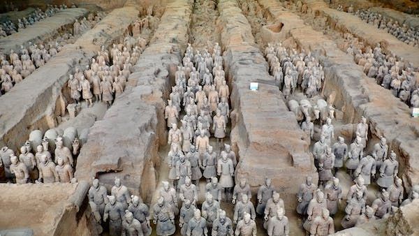 Centinaia di statue di guerrieri e cavalli in terracotta si trovano in formazione all'interno di fosse scavate.