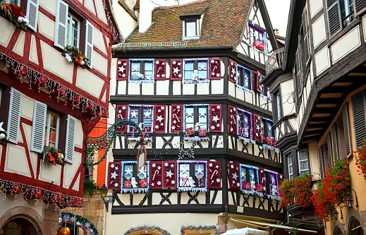 Colorati edifici a graticcio su una strada, adornati con festose decorazioni natalizie su finestre e persiane