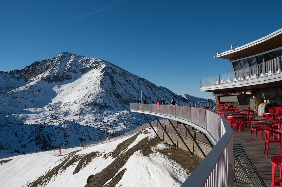 Un viaje en grupo de WeRoad en una plataforma de observación en un complejo de montaña, con vistas a picos nevados bajo un cielo azul claro.