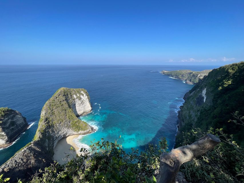 Veduta dall'alto di una costa verde e rocciosa con una spiaggia sabbiosa appartata e acque turchesi sotto un cielo azzurro.