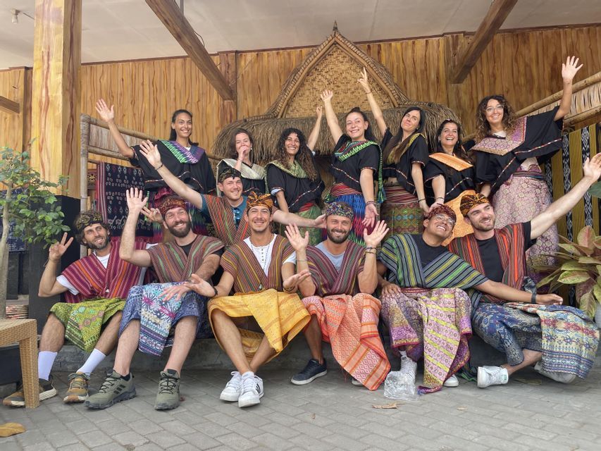 Eine WeRoad Gruppenreise, die für ein Foto posiert, alle lächeln und tragen farbenfrohe traditionelle Kleidung.