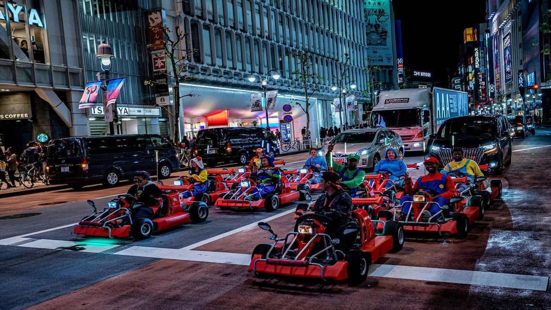 Un viaggio di gruppo WeRoad in costumi colorati guida go-kart rossi lungo una strada cittadina illuminata di notte.