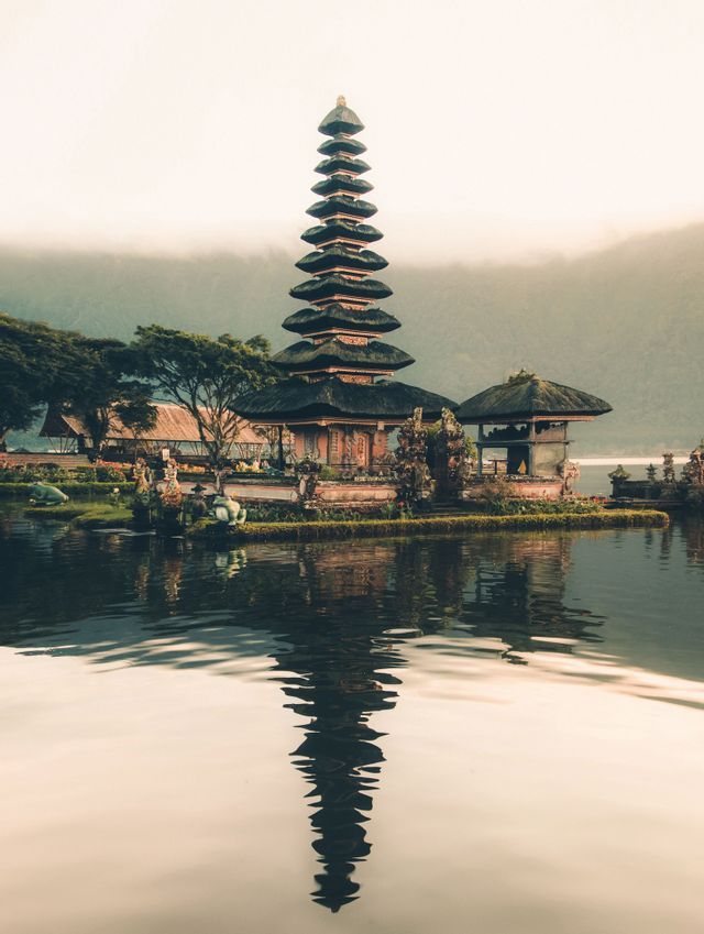 Un tempio alto e a più livelli sulla riva di un lago, con il suo riflesso visibile nell'acqua.