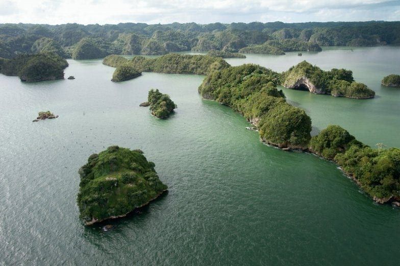 Vista aérea de una bahía llena de numerosas islas pequeñas y verdes bajo un cielo nublado.