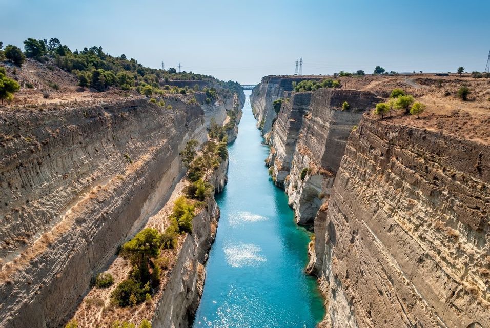 In una giornata di sole, un lungo e stretto canale dalle acque turchesi scorre tra ripide scogliere rocciose a strati.