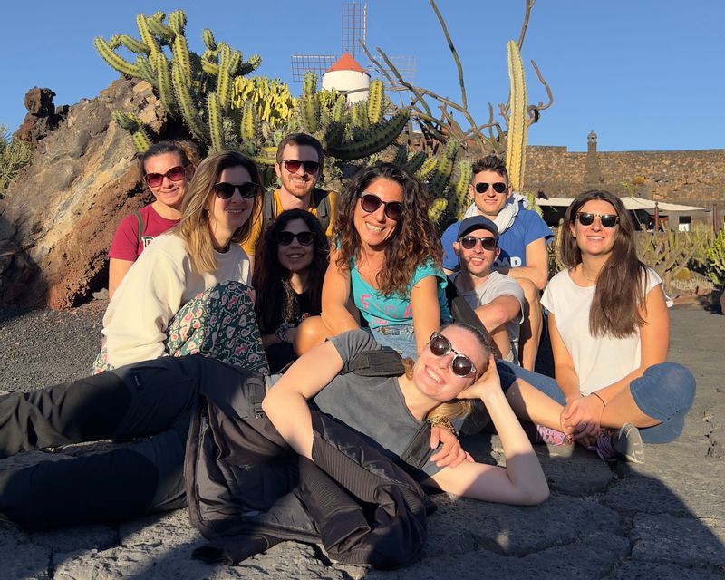 Un viaggio di gruppo WeRoad con persone in posa per una foto davanti a cactus e un mulino a vento.