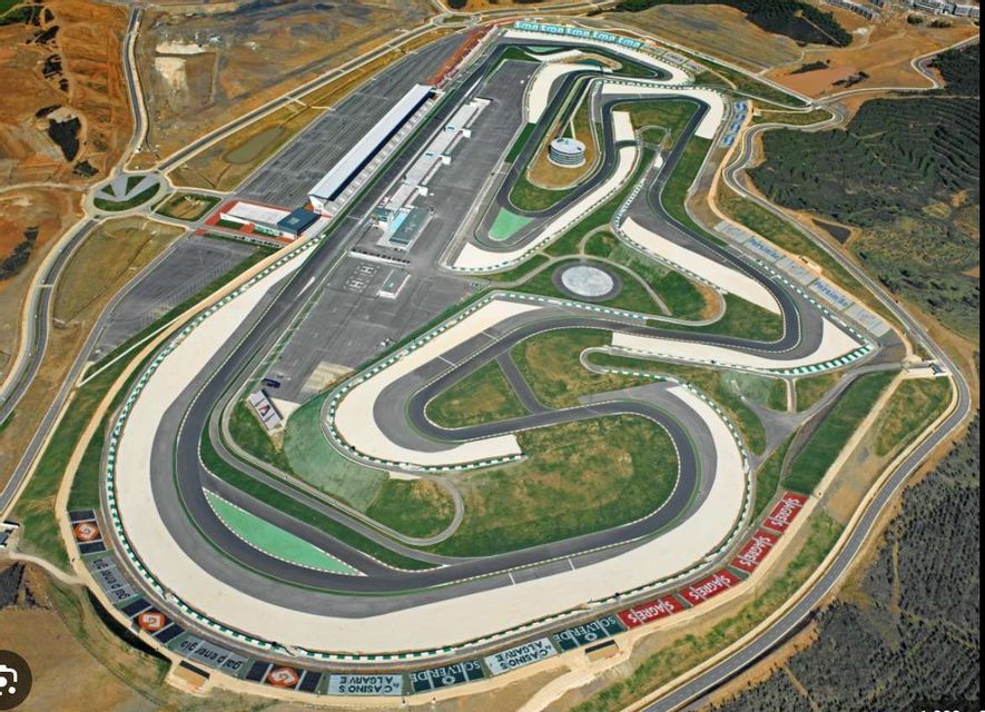 Una vista aerea di un grande e tortuoso circuito automobilistico, che mostra l'intera configurazione della pista, la corsia dei box e le tribune.