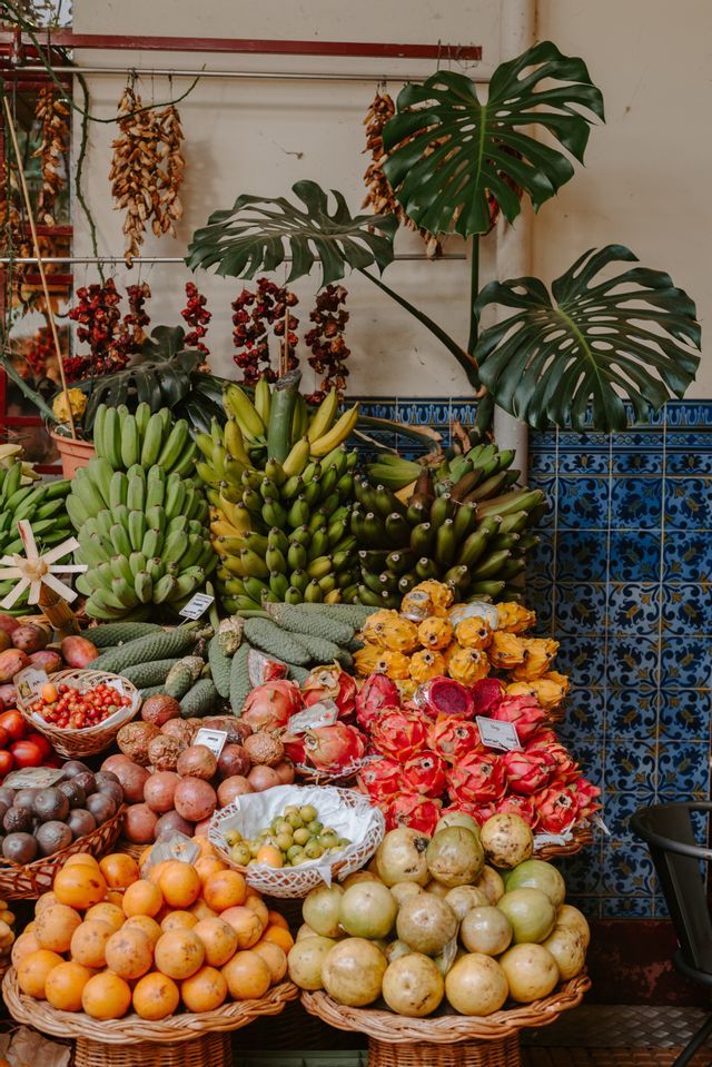 Un assortimento di frutti tropicali, tra cui banane e frutto del drago, esposti in cesti su una bancarella del mercato.
