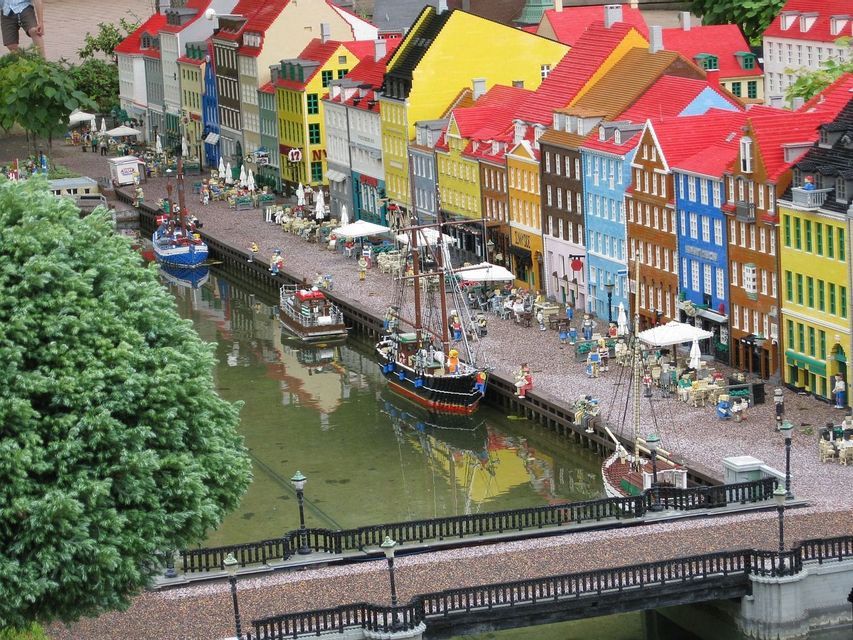 Una ciudad en miniatura de ladrillos LEGO, que representa un canal con barcos amarrados y un paseo marítimo con edificios coloridos.