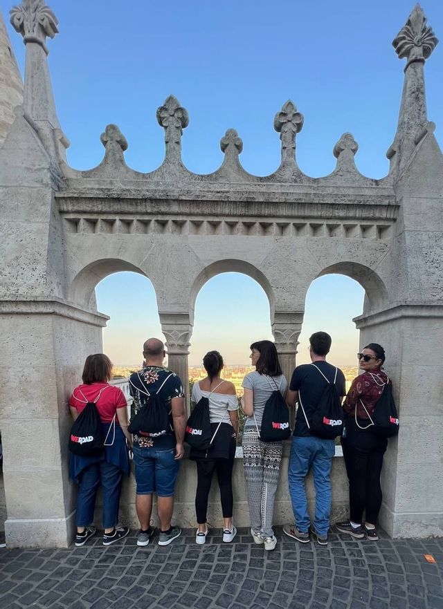 Eine WeRoad-Gruppentour von hinten gesehen, von einem gewölbten Steinbalkon aus mit Blick auf die Stadtlandschaft.