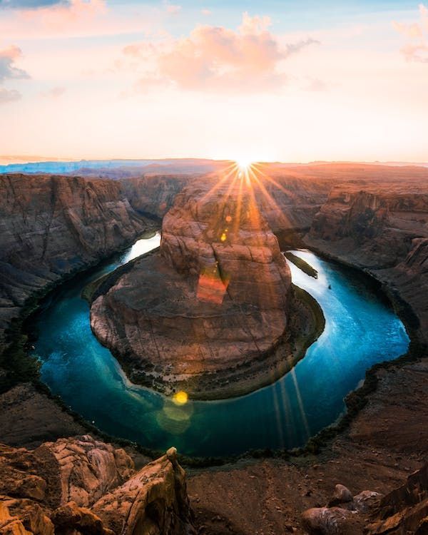 Una vista aerea di un fiume che forma un'ansa a ferro di cavallo attraverso un canyon profondo al tramonto, creando un effetto stellare.