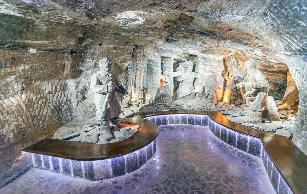 Lebensgroße Salzskulpturen von Bergleuten in einer beleuchteten Höhle.