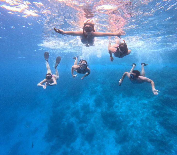 Quattro persone di un gruppo WeRoad che fanno snorkeling in acque cristalline, riprese dal basso.