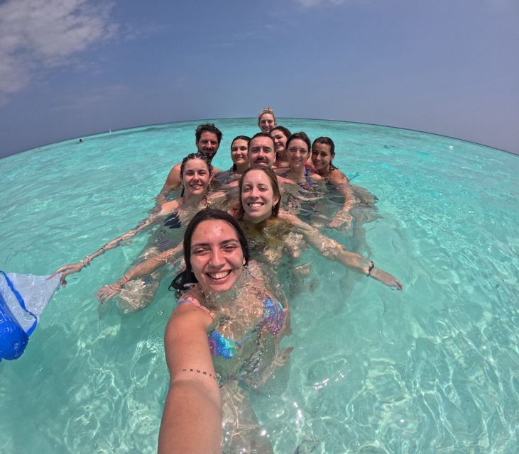 Un gruppo WeRoad si scatta un selfie sorridente mentre nuota in acque oceaniche limpide e turchesi.