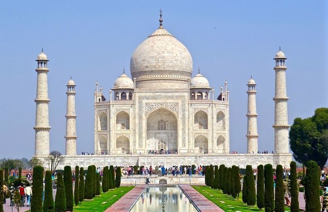 El mausoleo de mármol blanco Taj Mahal con su gran cúpula y minaretes, visto desde sus jardines formales y estanque reflectante.