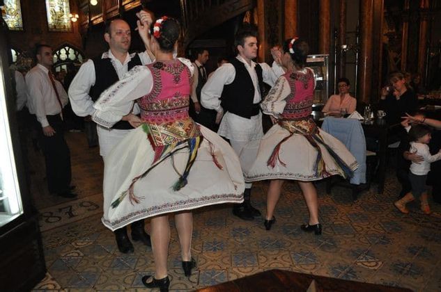 Parejas en trajes folclóricos tradicionales realizan un baile en un restaurante para los comensales.