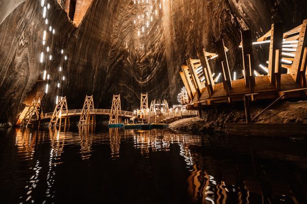 Un lago subterráneo dentro de una gran mina de sal iluminada con estructuras de madera y un puente.