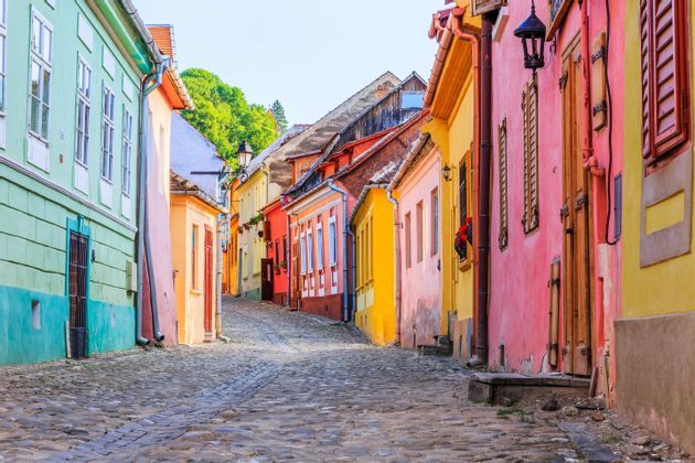 Edificios históricos coloridos bordean una calle adoquinada estrecha y sinuosa que asciende.